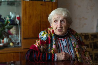 Masada oturan parlak elbiseli yaşlı bir büyükanne..