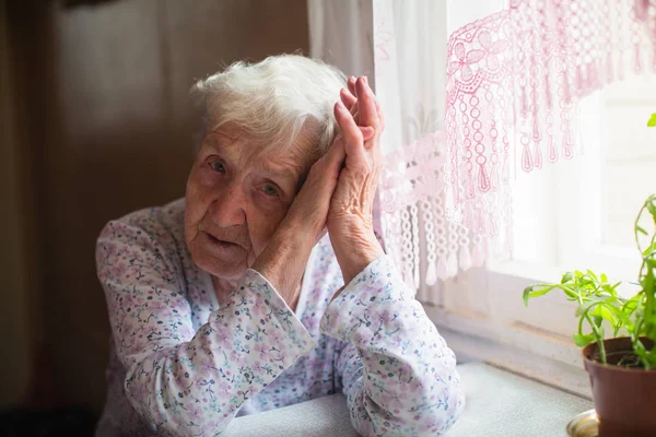一位悲伤的老妇人正坐在她家的桌子旁 — 图库照片