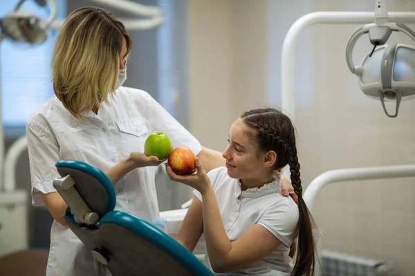 Dentysta Daje Jabłko Dla Uśmiechniętej Nastolatki Nowoczesnej Klinice Stomatologicznej — Zdjęcie stockowe
