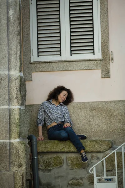 Kobieta Rasy Mieszanej Siedząca Przy Ścianie Domu Porto Portugalia — Zdjęcie stockowe