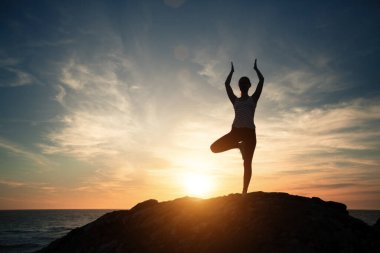 Fitness yogası yapan kadının silueti, deniz sahilinin batışında sabah egzersizleri.. 