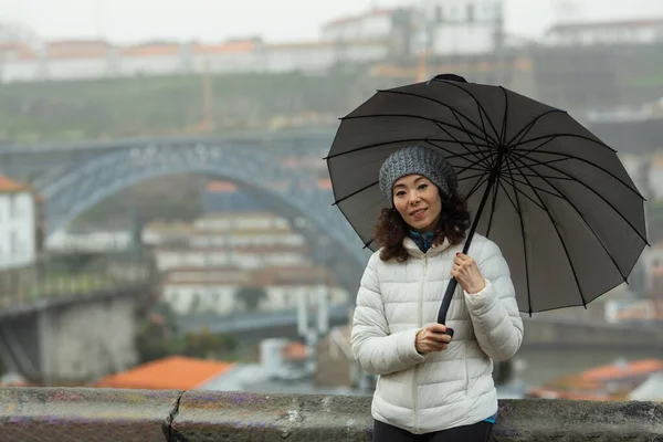 葡萄牙波尔图多姆路易斯一号桥的背景下 一名在多雾天气下带着雨伞的混血女游客 — 图库照片