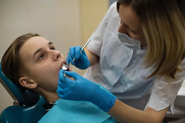 歯医者は歯科クリニックで男の歯の検査を行う — ストック写真