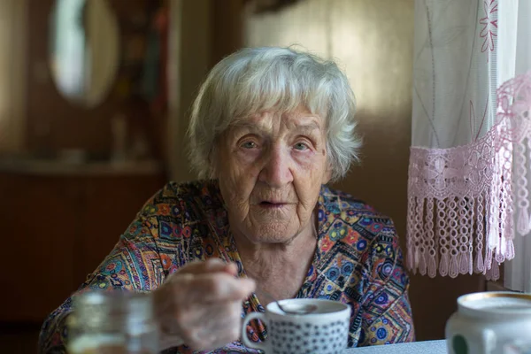 一个老妇人坐在厨房里的画像 — 图库照片
