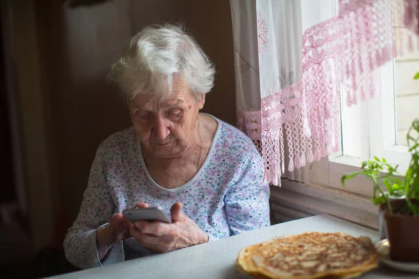 Starší Žena Sedí Chytrým Telefonem Rukou Doma — Stock fotografie