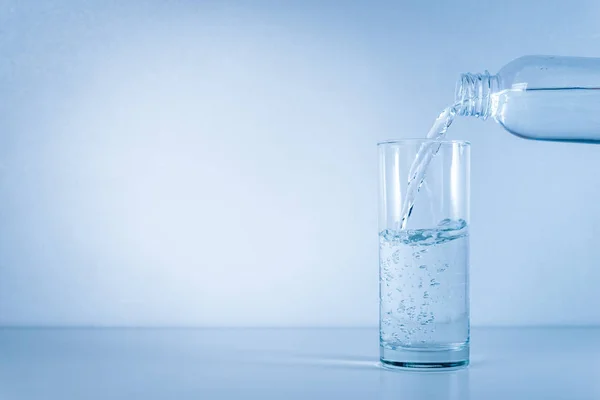 Despejar água da garrafa em vidro — Fotografia de Stock