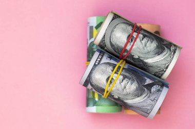 100 dolar, 50 ve 100 Euro 'luk banknotlar pembe arka planda.