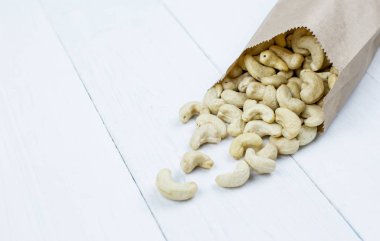 Tahta bir masada, kağıt bir torbada taze kaju fıstığı..