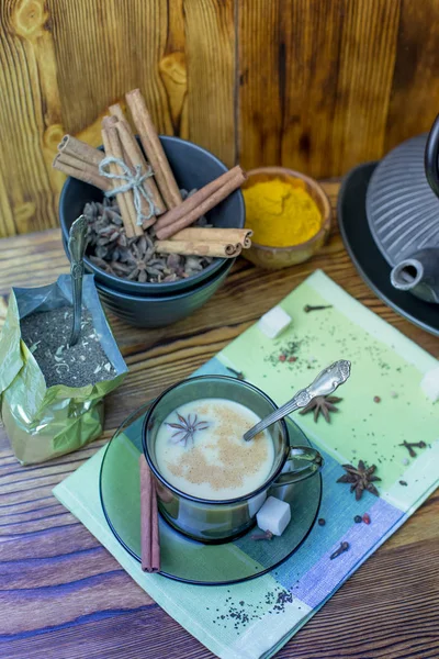 Masala tea. A Cup of traditional Indian tea masala tea with ingredients to prepare. Cinnamon, anise, sugar, black tea, pepper, cloves, turmeric on a wooden table.