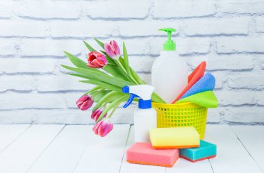 Spring cleaning holiday concept, supplies and tools for cleaning and spring flowers. Liquid disinfectants, sponges and cleaning cloths. Copy space