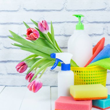Spring cleaning holiday concept, supplies and tools for cleaning and spring flowers. Liquid disinfectants, sponges and cleaning cloths. Copy space