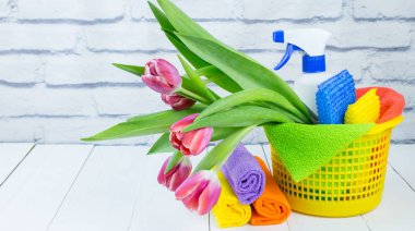 Spring cleaning holiday concept, supplies and tools for cleaning and spring flowers. Liquid disinfectants, sponges and cleaning cloths. Copy space