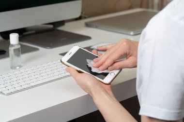 Kadınların ellerini eldivenle kapatın. Akıllı telefon ekranını dezenfektan beziyle silin.