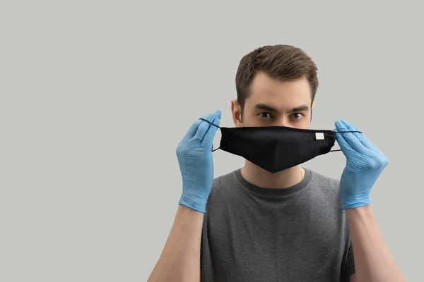 コロナウイルスに対して再利用可能なマスクを身に着けている若いヨーロッパの男は ウイルス白 灰色の背景から防ぐために外科マスクを身に着けている19人をCovidコロナウイルスパンデミック — ストック写真