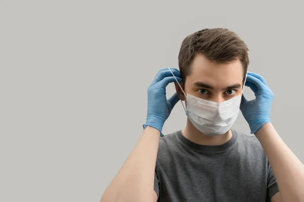 コロナウイルスに対してマスクを身に着けている若いヨーロッパ人男性は ウイルス白 灰色の背景から防ぐために外科用マスクを身に着けている19人をCovidコロナウイルスパンデミック — ストック写真