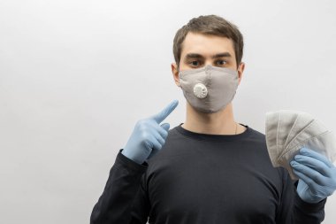 Corona virüsüne karşı maske takan genç Avrupalı bir adam ve virüsün beyaz arka plan Corona virüsünü önlemesi için tekrar kullanılabilir ameliyat maskesi takan 19 kişiyi başparmağında oynatıyor. 