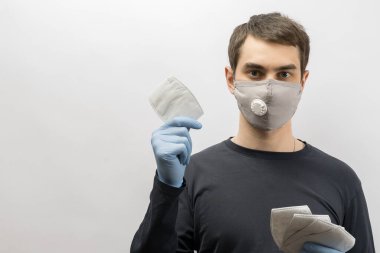 Corona virüsüne karşı maske takan genç Avrupalı bir adam ve virüsün beyaz arka plan Corona virüsünü önlemesi için tekrar kullanılabilir ameliyat maskesi takan 19 kişiyi başparmağında oynatıyor. 