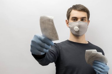 Corona virüsüne karşı maske takan genç Avrupalı bir adam ve virüsün beyaz arka plan Corona virüsünü önlemesi için tekrar kullanılabilir ameliyat maskesi takan 19 kişiyi başparmağında oynatıyor. 