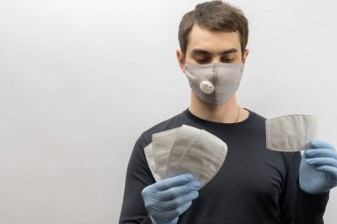 Corona virüsüne karşı maske takan genç Avrupalı bir adam ve virüsün beyaz arka plan Corona virüsünü önlemesi için tekrar kullanılabilir ameliyat maskesi takan 19 kişiyi başparmağında oynatıyor. 