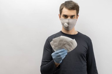 Corona virüsüne karşı maske takan genç Avrupalı bir adam ve virüsün beyaz arka plan Corona virüsünü önlemesi için tekrar kullanılabilir ameliyat maskesi takan 19 kişiyi başparmağında oynatıyor. 