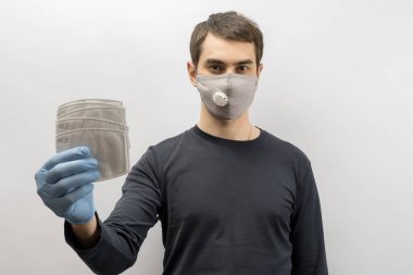 Corona virüsüne karşı maske takan genç Avrupalı bir adam ve virüsün beyaz arka plan Corona virüsünü önlemesi için tekrar kullanılabilir ameliyat maskesi takan 19 kişiyi başparmağında oynatıyor. 