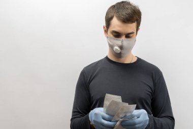 Corona virüsüne karşı maske takan genç Avrupalı bir adam ve virüsün beyaz arka plan Corona virüsünü önlemesi için tekrar kullanılabilir ameliyat maskesi takan 19 kişiyi başparmağında oynatıyor. 