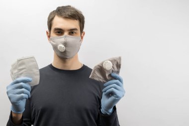 Corona virüsüne karşı maske takan genç Avrupalı bir adam ve virüsün beyaz arka plan Corona virüsünü önlemesi için tekrar kullanılabilir ameliyat maskesi takan 19 kişiyi başparmağında oynatıyor. 