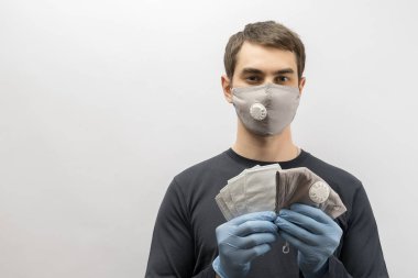 Corona virüsüne karşı maske takan genç Avrupalı bir adam ve virüsün beyaz arka plan Corona virüsünü önlemesi için tekrar kullanılabilir ameliyat maskesi takan 19 kişiyi başparmağında oynatıyor. 