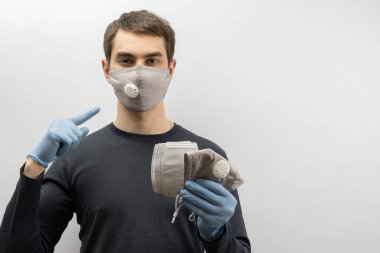 Corona virüsüne karşı maske takan genç Avrupalı bir adam ve virüsün beyaz arka plan Corona virüsünü önlemesi için tekrar kullanılabilir ameliyat maskesi takan 19 kişiyi başparmağında oynatıyor. 