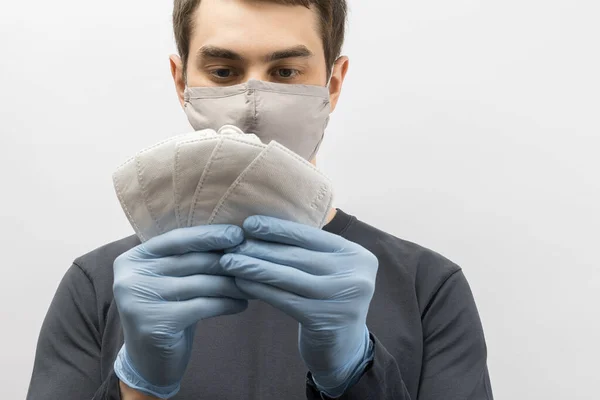 Young european man wearing mask against the corona virus and thumbs up covid 19 man wearing reusable surgical mask to prevent from virus white\grey background Corona virus pandemic