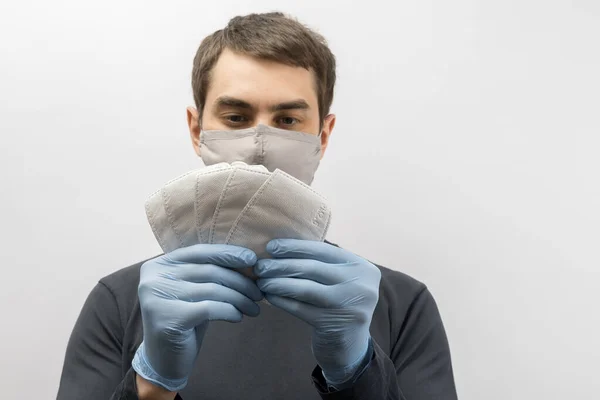 Young european man wearing mask against the corona virus and thumbs up covid 19 man wearing reusable surgical mask to prevent from virus white\grey background Corona virus pandemic