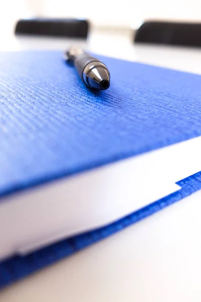 Μαύρο Στυλό Ένα Μπλε Σημειωματάριο Κάθεται Ένα Τραπέζι Ένα Γραφείο — Φωτογραφία Αρχείου