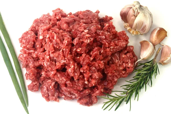 Carne macinata cruda isolata su fondo bianco con foglie verdi e condimenti . — Foto Stock