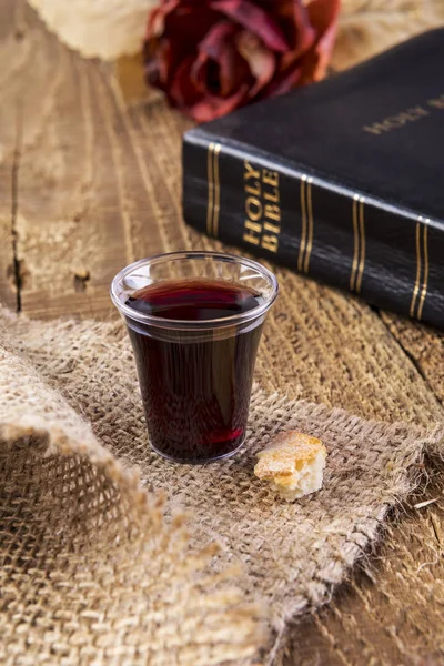 Nemen de communie. Beker van glas met rode wijn, brood en Heilige Bijbel. — Stockfoto