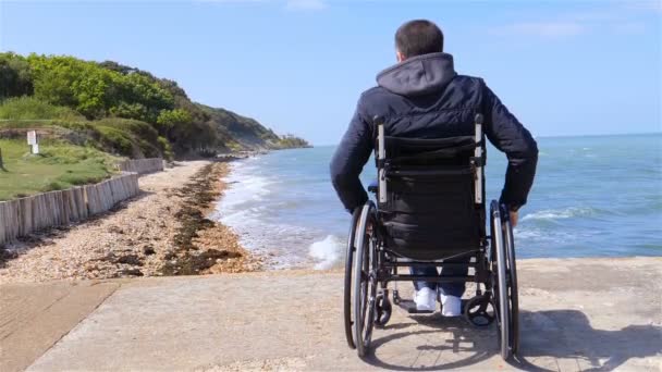 Спина инвалида в инвалидной коляске на пляже замедленной съемки — стоковое видео