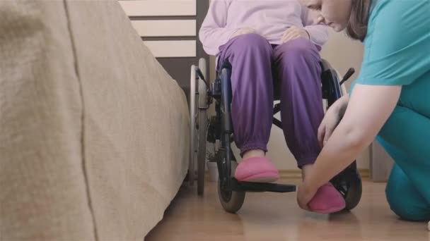 junge Krankenschwester kümmert sich um ältere behinderte Frau im Rollstuhl