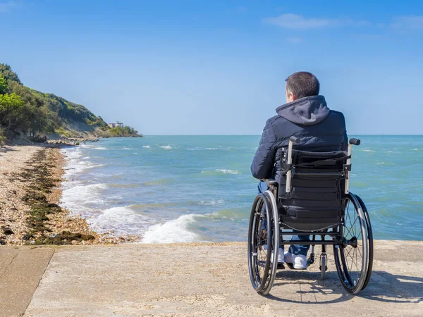Costas de homem com deficiência em cadeira de rodas na praia — Fotografia de Stock