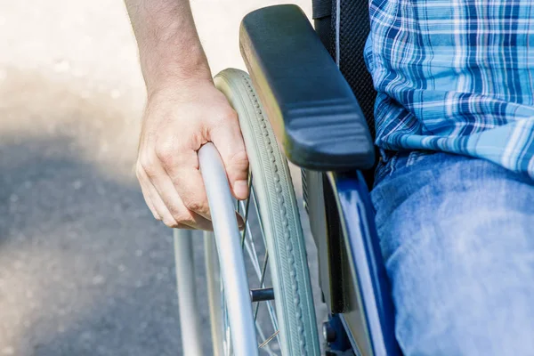 Mão de jovem na roda da cadeira de rodas — Fotografia de Stock