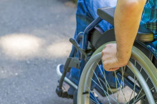 Mão de jovem na roda da cadeira de rodas — Fotografia de Stock
