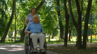 Üst düzey kadın koca tekerlekli sandalyede açık havada iterek