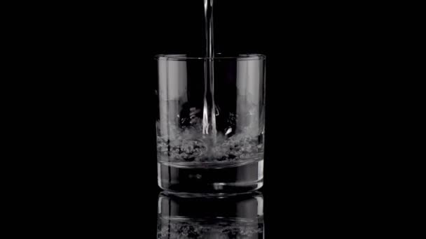 Remplissage d'un verre d'eau sur noir 