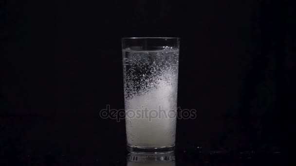 Comprimé effervescent tombant dans un verre plein d'eau 