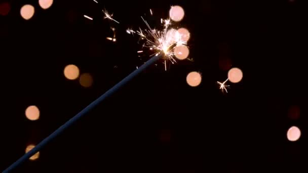 Sparkler ardiendo delante de las luces del ambiente en cámara lenta — Vídeos de Stock