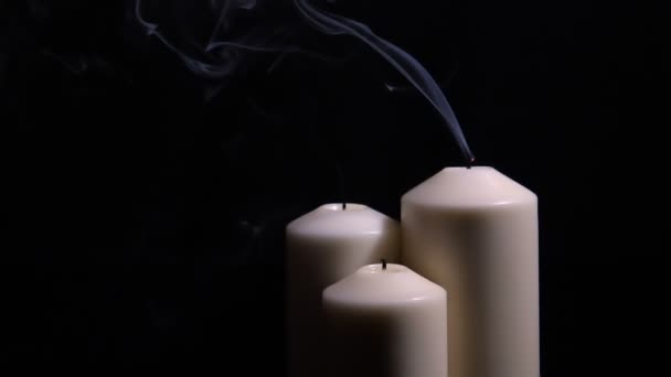 Три погасшие свечи с дымом на черном фоне — стоковое видео