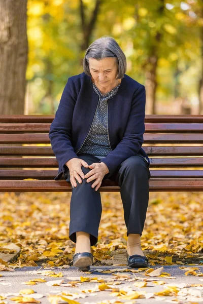 Senior kobieta o ból kolan, chodzenie w parku — Zdjęcie stockowe