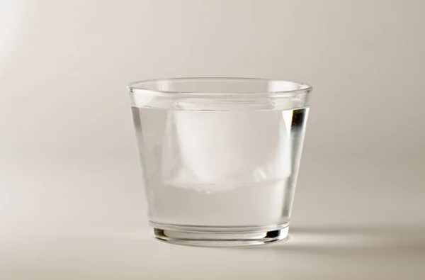 Physics. Ice cube floating over water. — Stock Photo, Image