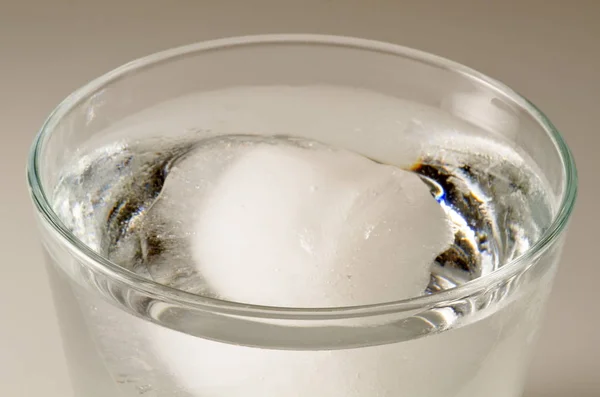 Física. Cubo de hielo flotando sobre el agua . — Foto de Stock