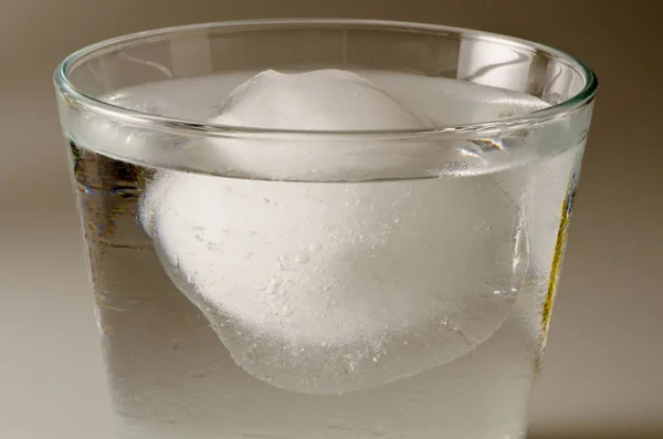 Physics. Ice cube floating over water. — Stock Photo, Image