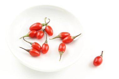 Fotokopi alanı olan beyaz arka planda izole edilmiş beyaz bir kasede taze goji üzümleri.