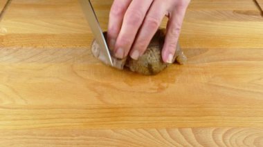 Mutfak bıçağıyla ahşap bir kesme tahtasının üzerinde pişirilmiş bir et bıçağını parçalara ayırmak.